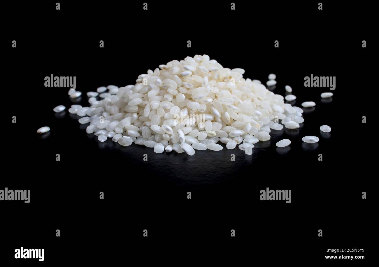 Riso bianco crudo e secco isolato su sfondo nero. Cumulo/cumulo Foto Stock