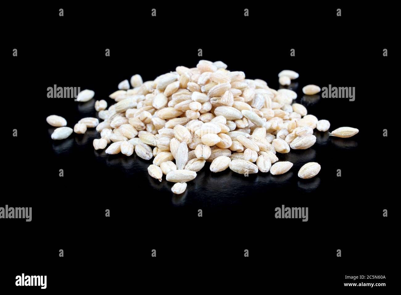 Gruppo di grani di orzo crudo isolato su sfondo nero. Foto Stock