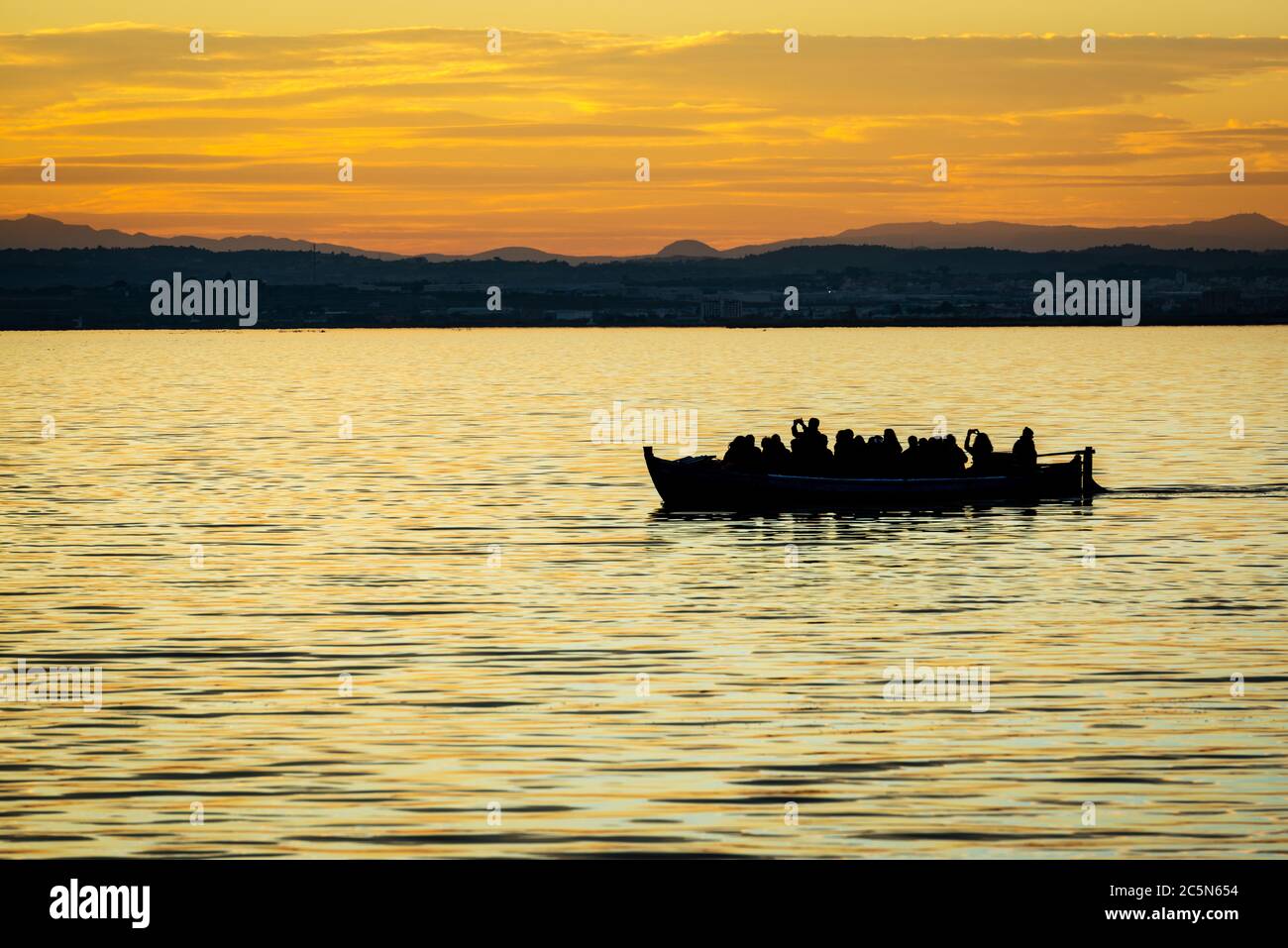 Silhouette di una piccola barca tradizionale al tramonto nell'Albufera a Valencia, una laguna d'acqua dolce e un estuario nella Spagna orientale. Foto Stock