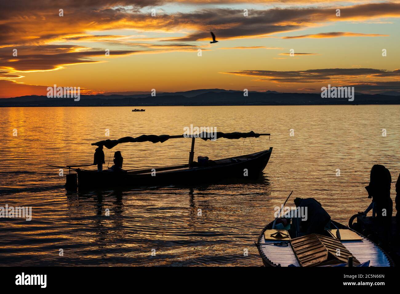 Silhouette di una piccola barca tradizionale al tramonto nell'Albufera a Valencia, una laguna d'acqua dolce e un estuario nella Spagna orientale. Foto Stock