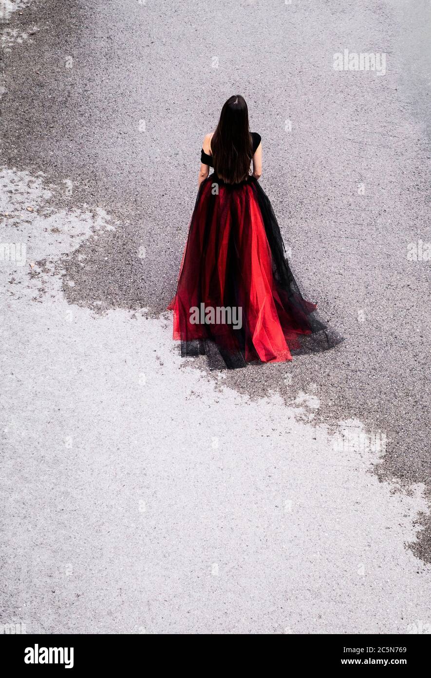 Donna in abito che cammina su una strada parzialmente bagnata Foto Stock