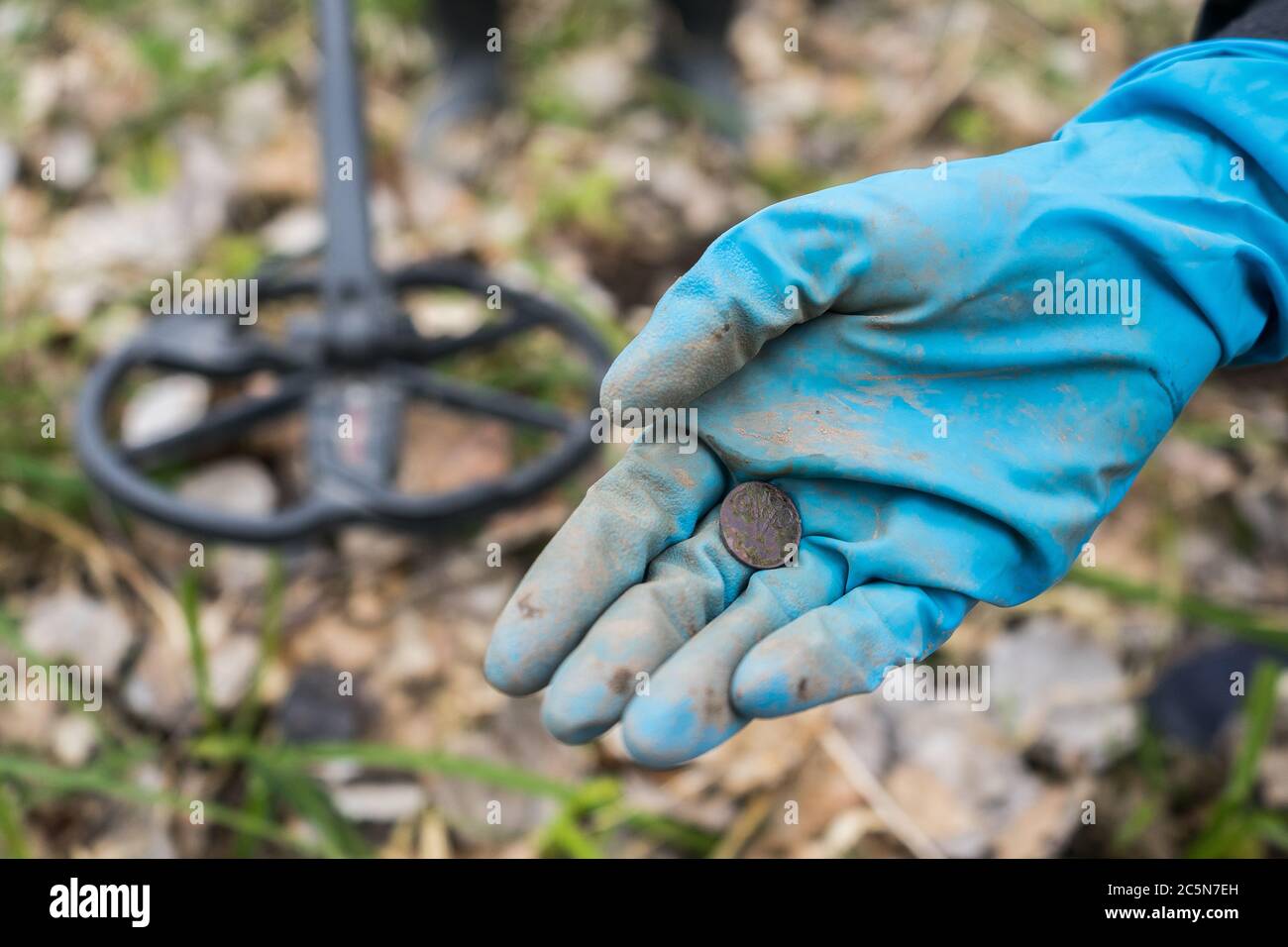 Trovato vecchia moneta nella mano del digger. Un digger guantato di gomma ha trovato una moneta Foto Stock