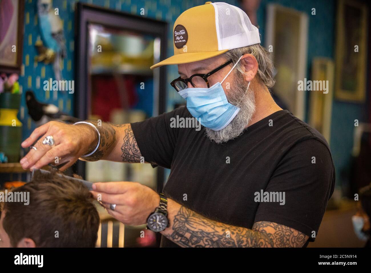 Barbiere taglio capelli indossare la maschera DPI al parrucchiere nei primi giorni di blocco alleggerimento durante la pandemia di Coronavirus. Inghilterra Luglio 2020 Foto Stock
