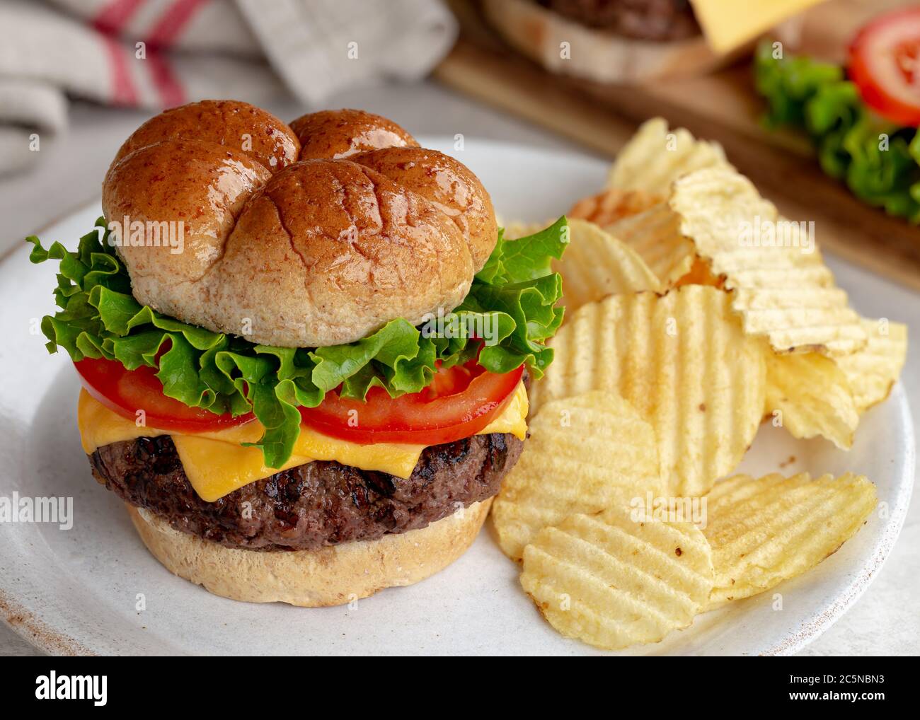 Succosa cheeseburger alla griglia con lattuga e patatine e pomodoro su un piatto Foto Stock
