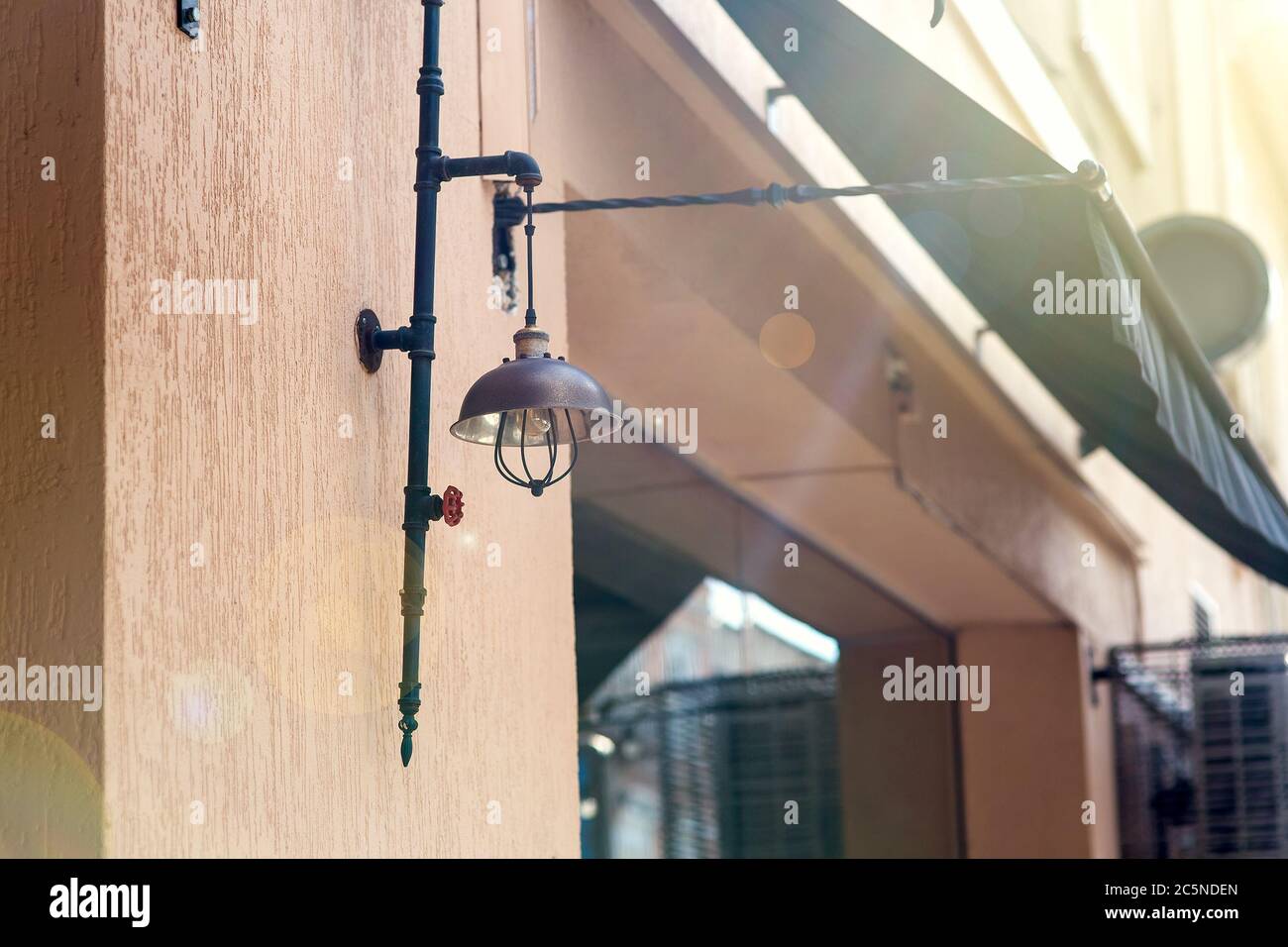 illuminazione street lampione in un loft di colore scuro sulla facciata di un caffè con una finestra e una visiera per l'ombra dal sole con un'illuminazione solare. Foto Stock