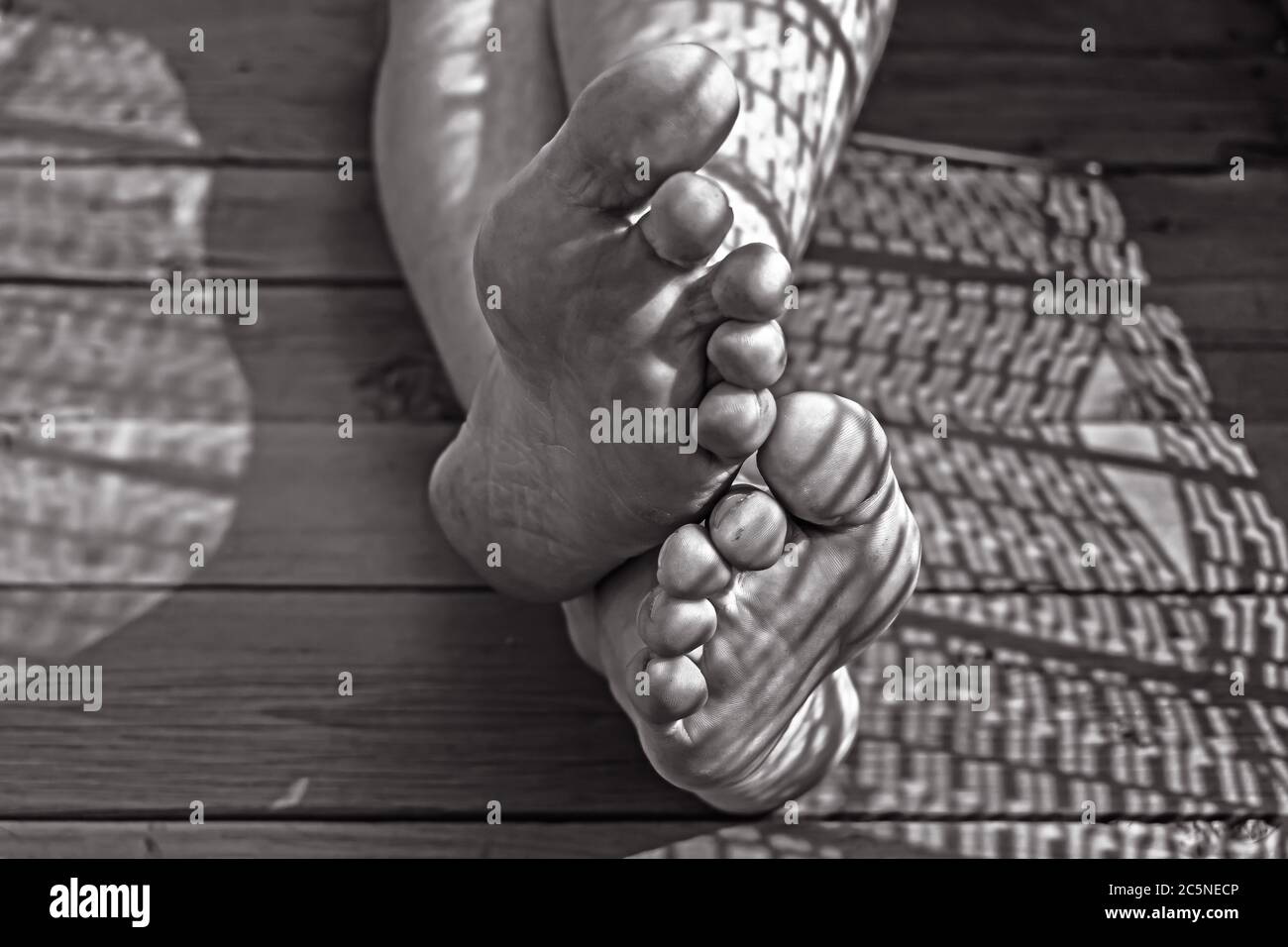 Gambe sporche di un lavoratore stanco da vicino su un pavimento di legno Foto Stock