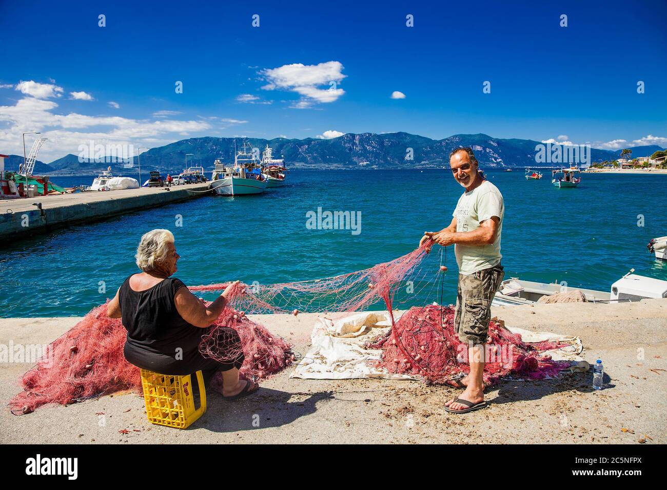 Agios Georgios Lichados Evia , Grecia -10 giugno 2018: Ago con filo in pescatore e le mani di sua moglie riparazione rete per la pesca. EVIA , Grecia. Foto Stock