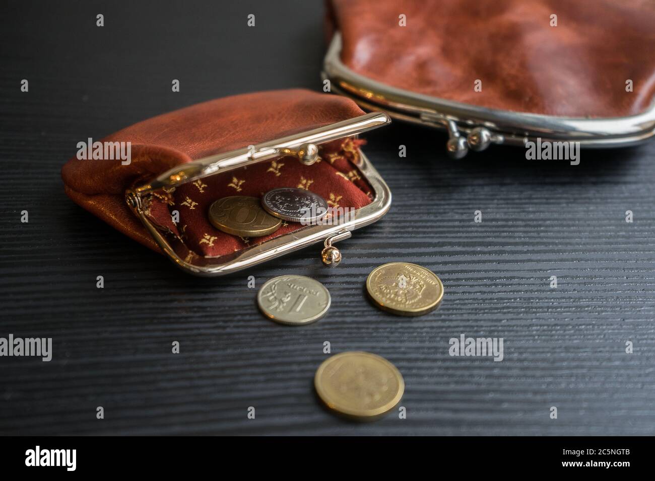 Ultimo denaro nel portafoglio. Le monete fuoriescono dal radicule sul tavolo. Foto Stock