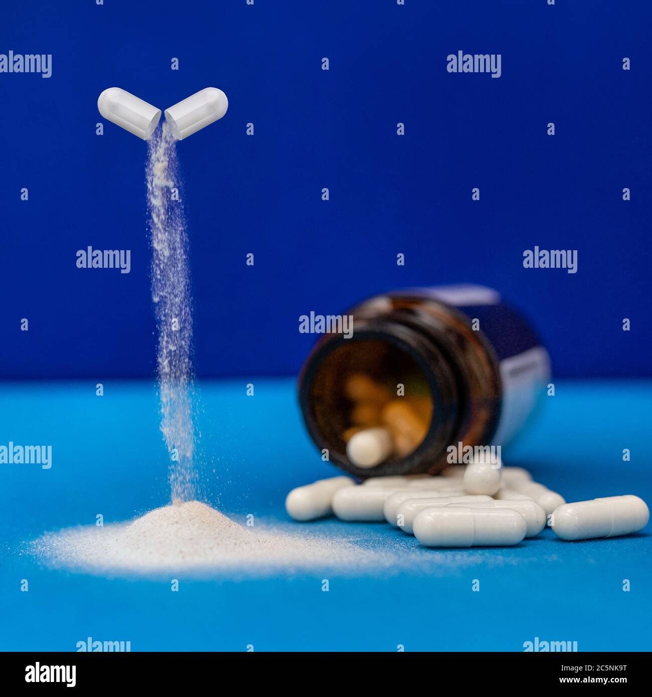 Capsula di farmaco che versa con un sacco di capsule bianche, pillole Foto Stock