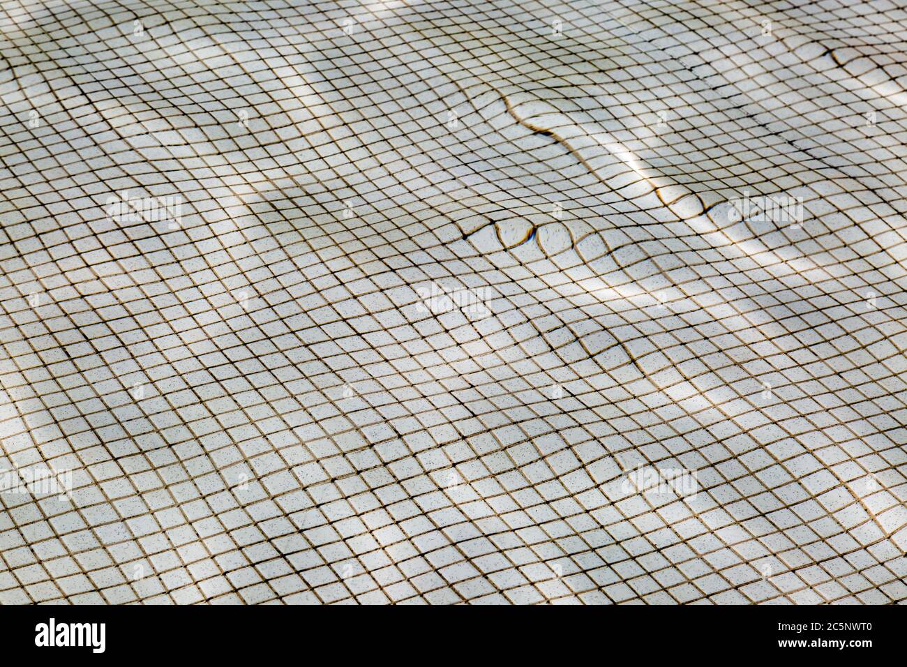 Guardando giù le piastrelle sul fondo di una piscina, distorte attraverso l'acqua Foto Stock