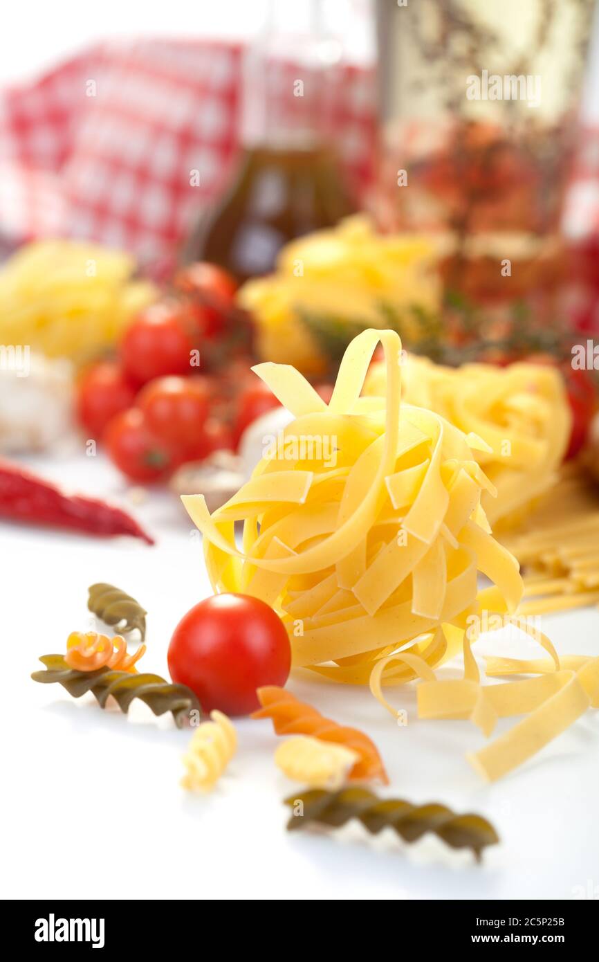 Gustosi e appetitosi classici spaghetti italiani con pomodoro e pasta in prima linea. Olio d'oliva, funghi e verdure sullo sfondo. Foto Stock