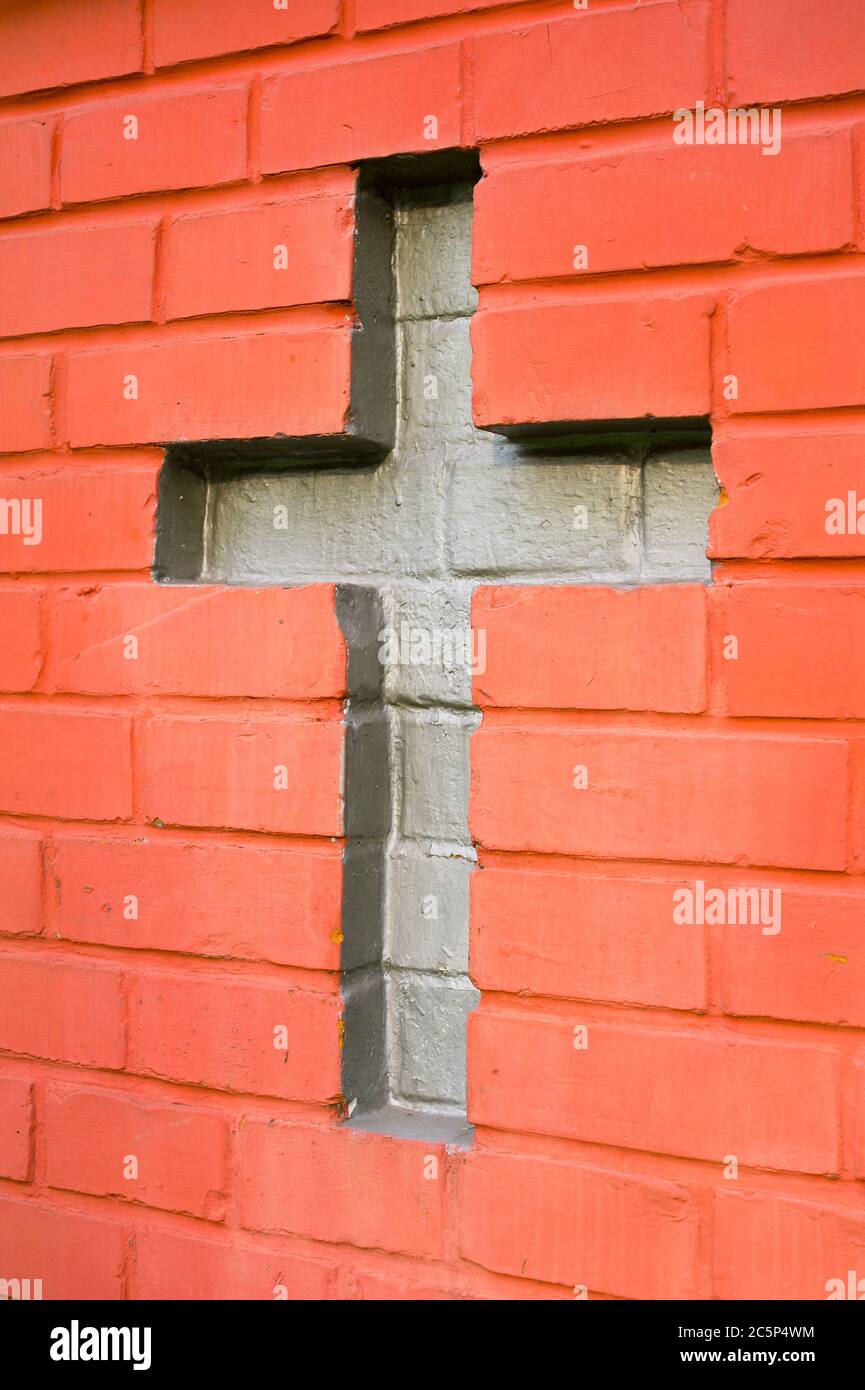 Parete fatta di mattoni rossi. Croce cristiana tra mattoni - simbolo del cristianesimo Foto Stock