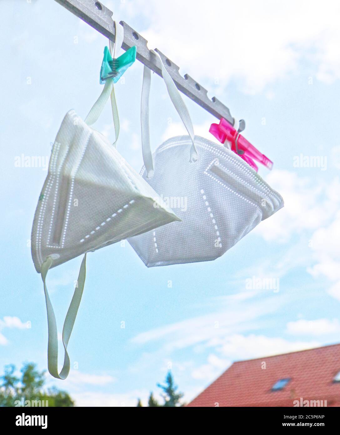 maschere di protezione covide appese al sole sul balcone dopo la disinfezione Foto Stock