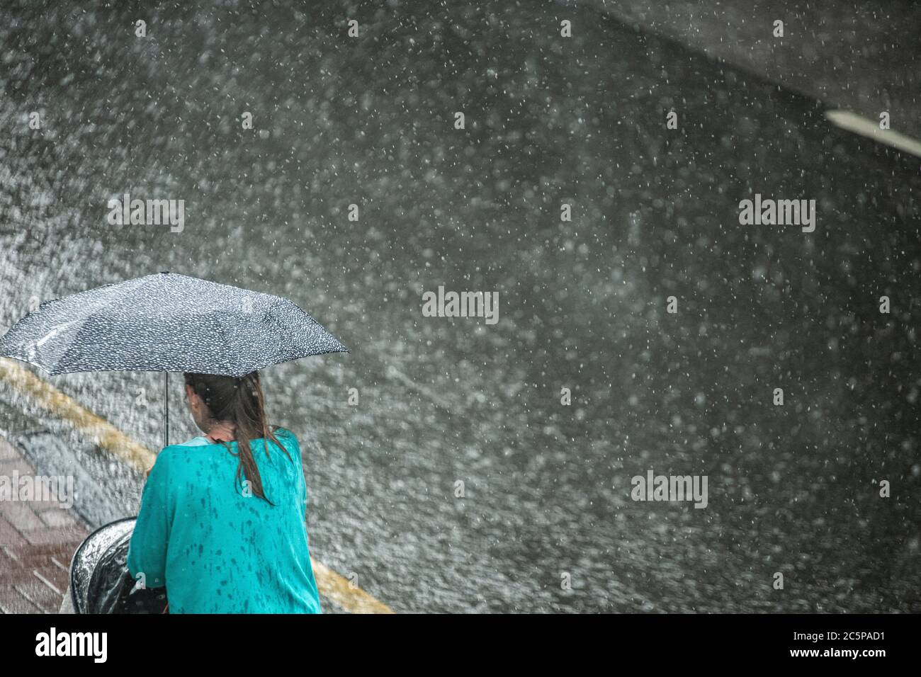 Una donna cammina nella pioggia battente con una passeggino Foto Stock