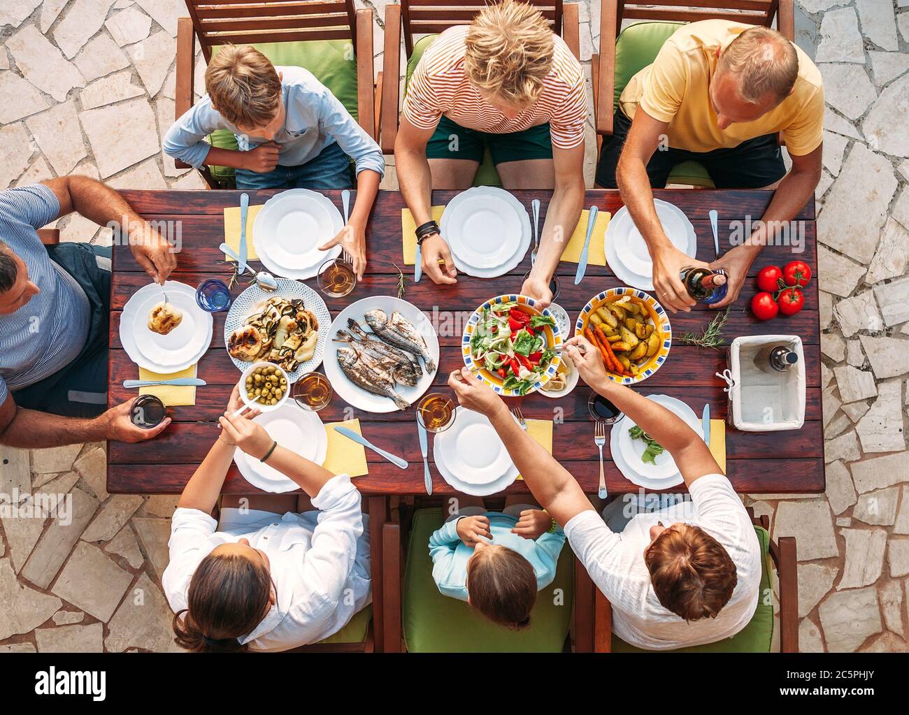 Grande cena multigenerazionale in corso. Immagine vista dall'alto sul tavolo con cibo e mani. Consumo alimentare e concetto di famiglia multigenerazionale ima Foto Stock