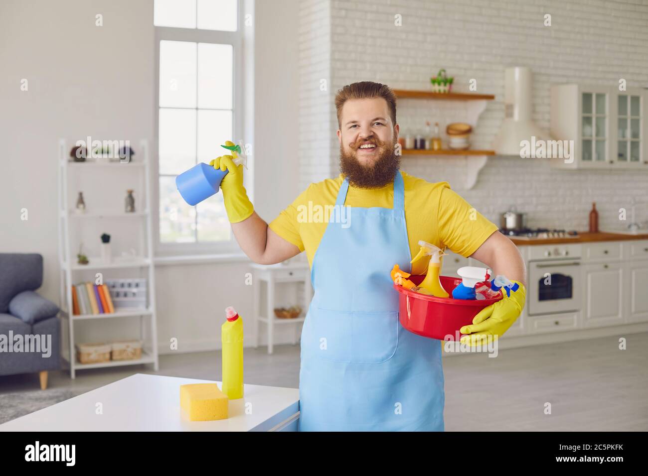 Un uomo grasso divertente in un grembiule e guanti di pulizia