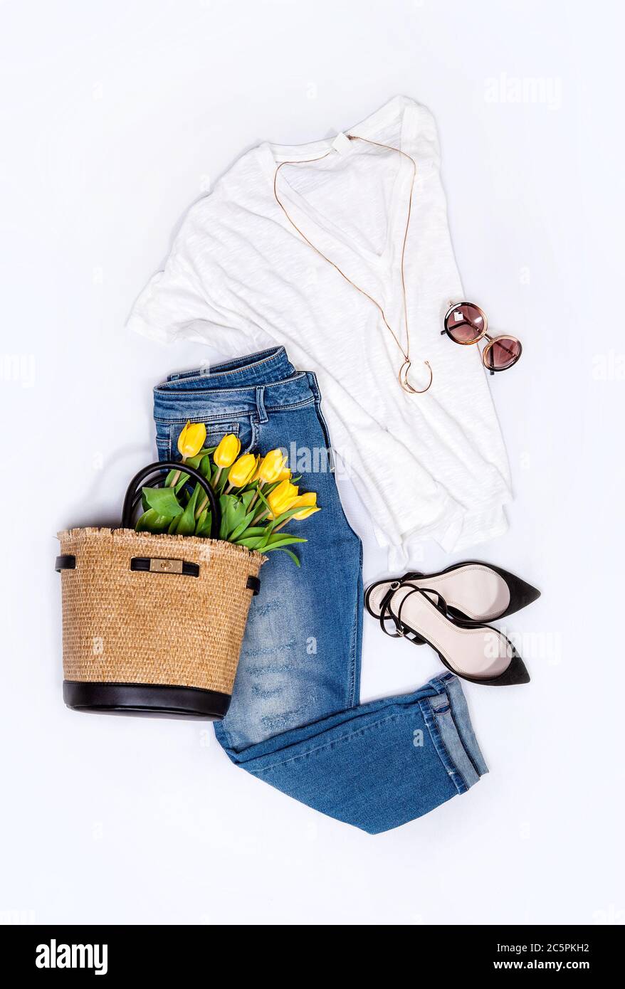 Primavera estate Basic denim casual città tendenza outfit per donna: Jeans, blusa, scarpe, collana dorata, occhiali da sole e borsa piena di tulipani gialli. Foto Stock