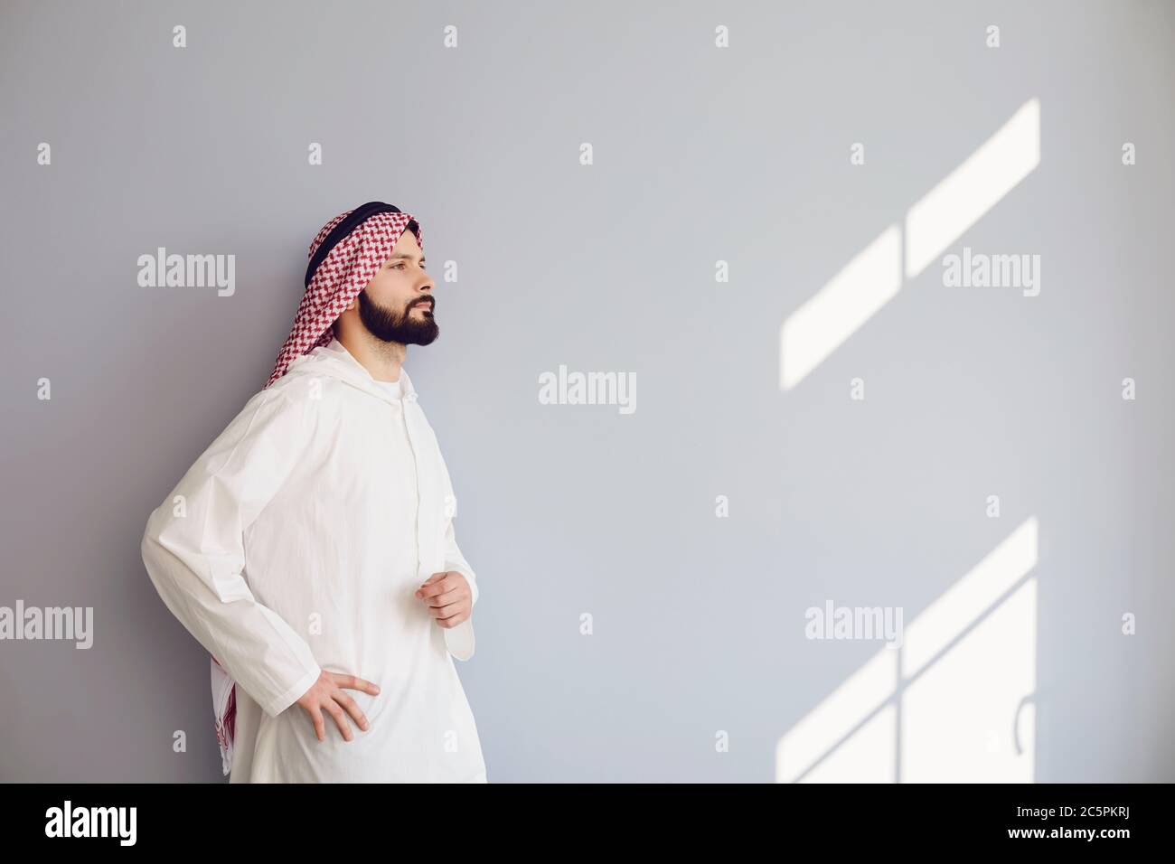 Uomo arabo sicuro guarda su sfondo grigio Foto Stock