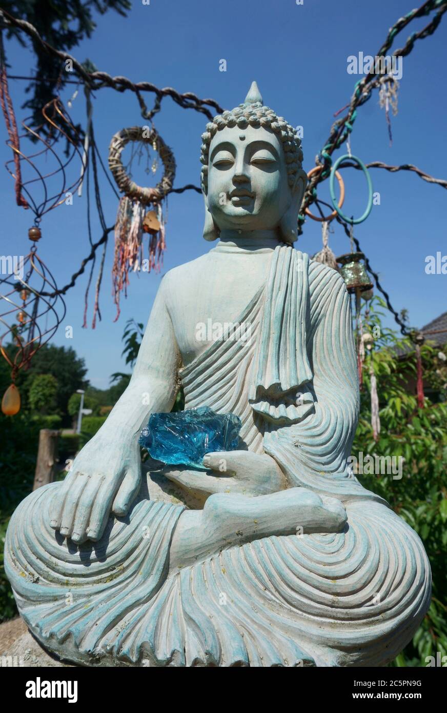 Statua di Buddha nel nostro giardino. C'è una pietra di vetro blu sul suo grembo. Il gesto della mano: Toccare la Terra, che rappresenta il momento del risveglio Foto Stock