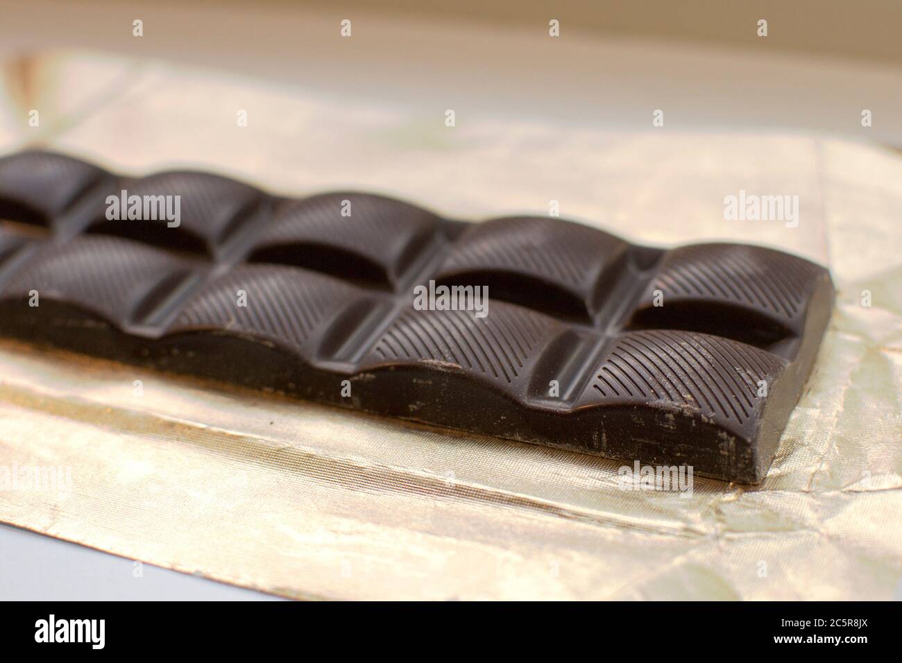 Barretta di caramelle al cioccolato fondente su lamina d'oro Foto Stock