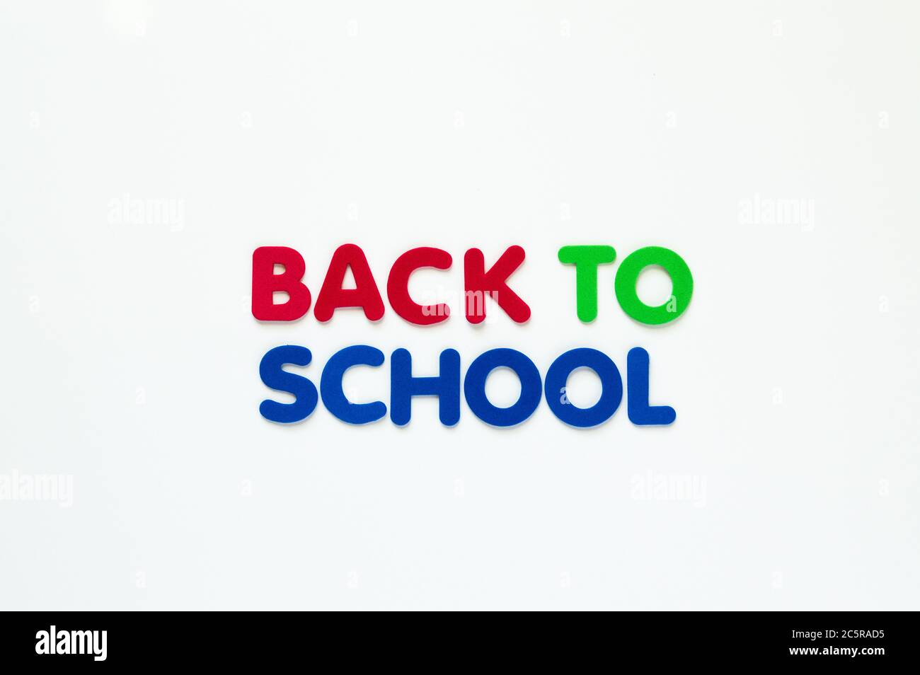 Lettere in schiuma rossa, verde e blu con la scritta "Back to School" in due righe isolate su bianco Foto Stock