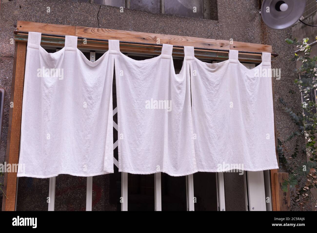 Il tessuto simile a una tenda che pende di fronte ai ristoranti e negozi tradizionali giapponesi serve non solo come un cartello, ma ha un significato più grande, Foto Stock