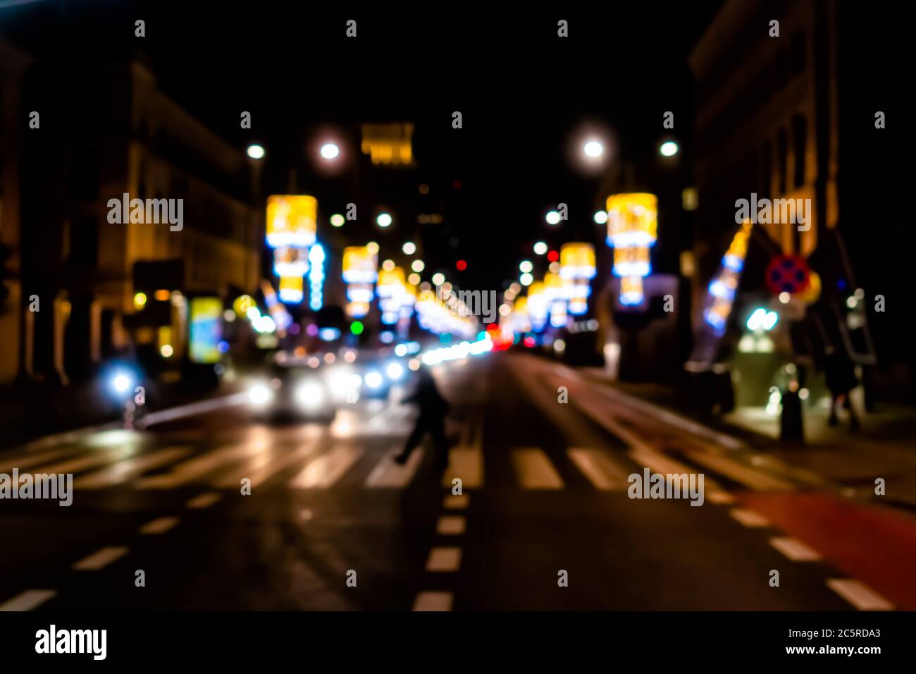 Varsavia, Polonia strada scura di notte nella città vecchia di Warszawa con le persone che attraversano a piedi al crosswalk e le illuminazioni di Natale bokeh astratto bac Foto Stock