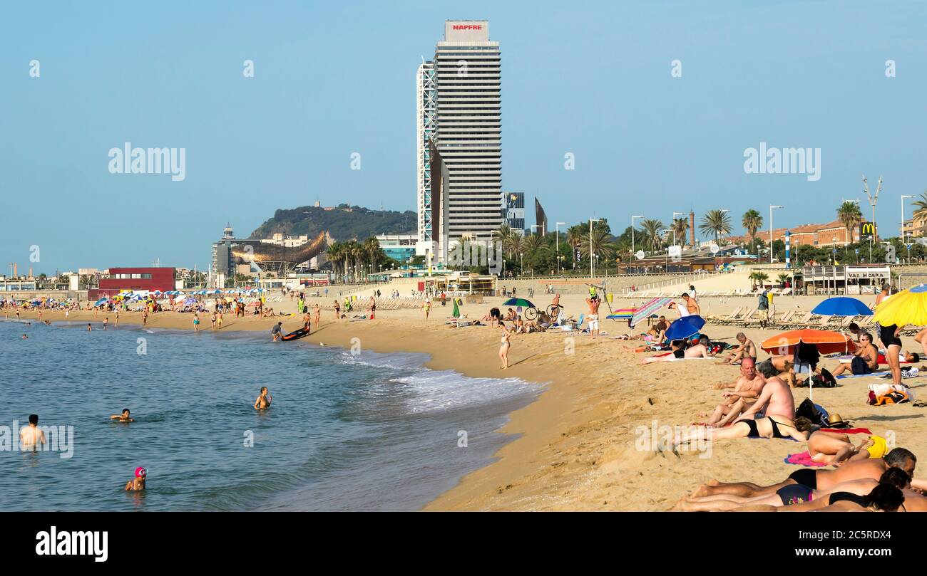 BARCELLONA, SPAGNA - 5 LUGLIO 2015: Spiaggia di Barceloneta e grattacielo Torre Mapfre nel Porto Olimpico. Prende il nome dal suo proprietario, Mapfre, un'assicurazione Foto Stock