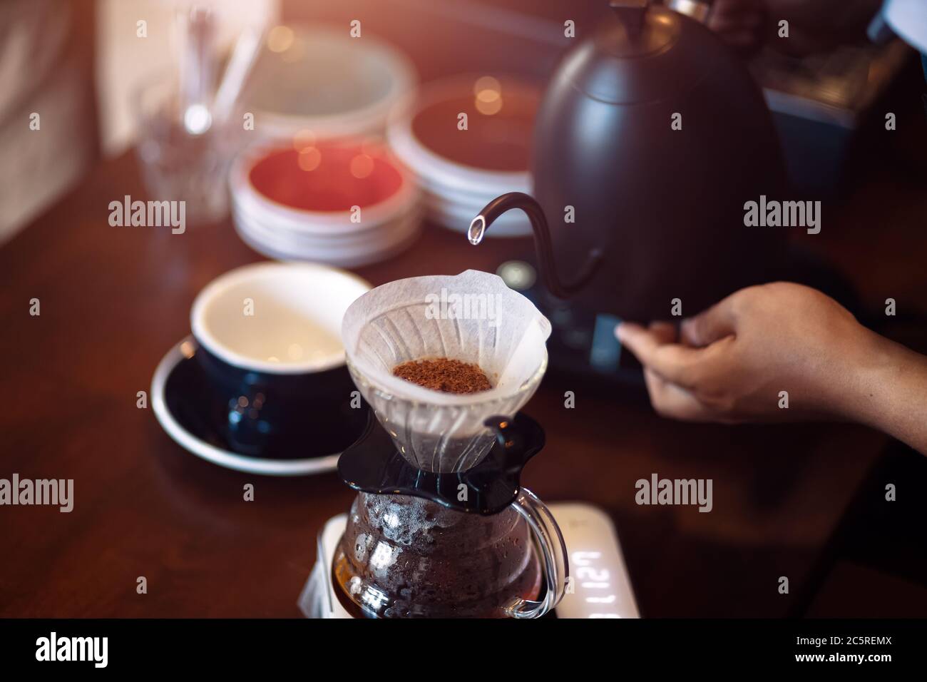 barista che versa acqua bollente dal bollitore alla macchina per caffè a goccia. Foto Stock