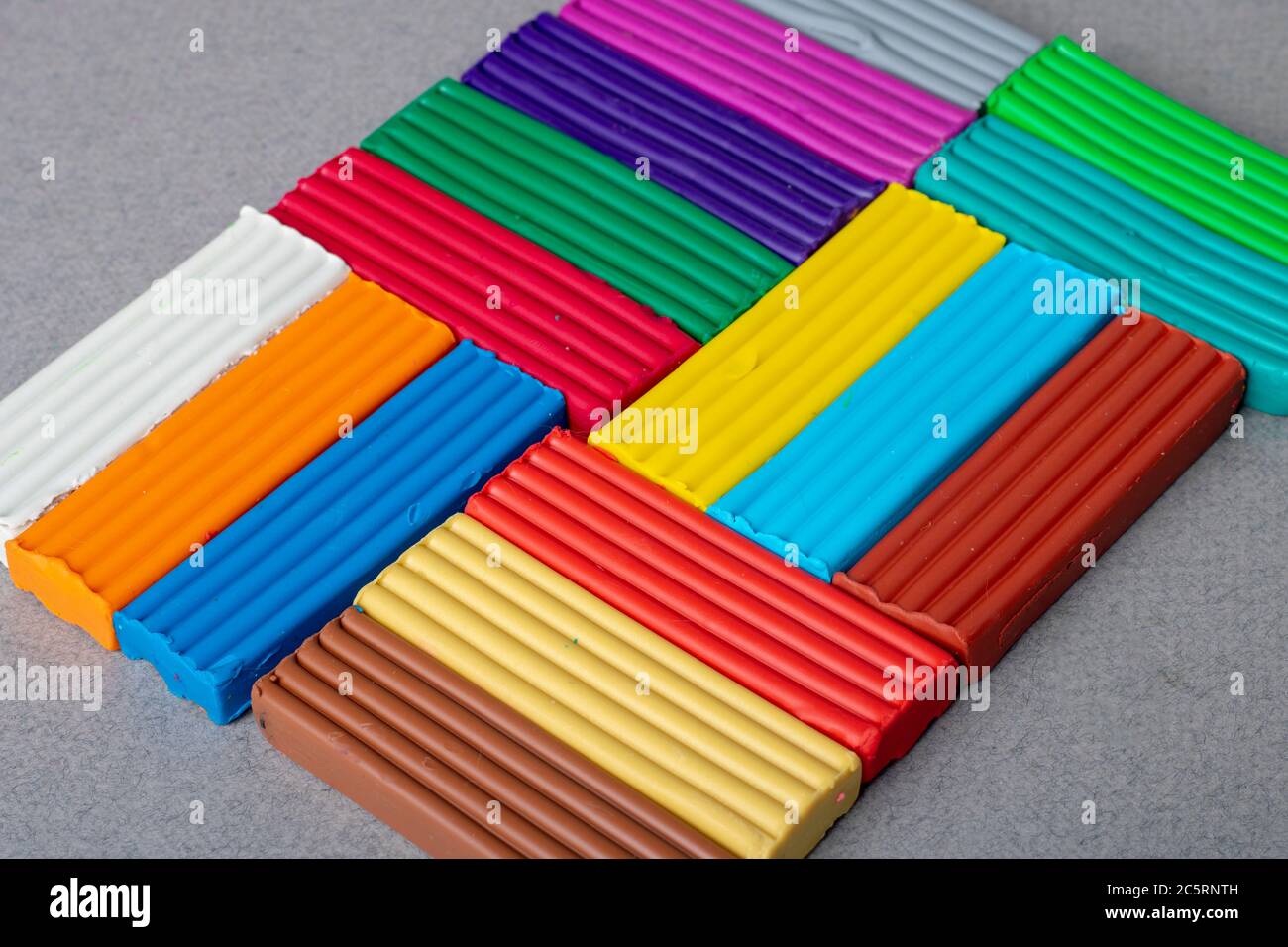 Set di bastoncini di plastilina su sfondo grigio. Vista orizzontale dall'alto, copia libera del vaso. Giallo, rosa, marrone, rosso, blu, arancio e argilla bianca Foto Stock
