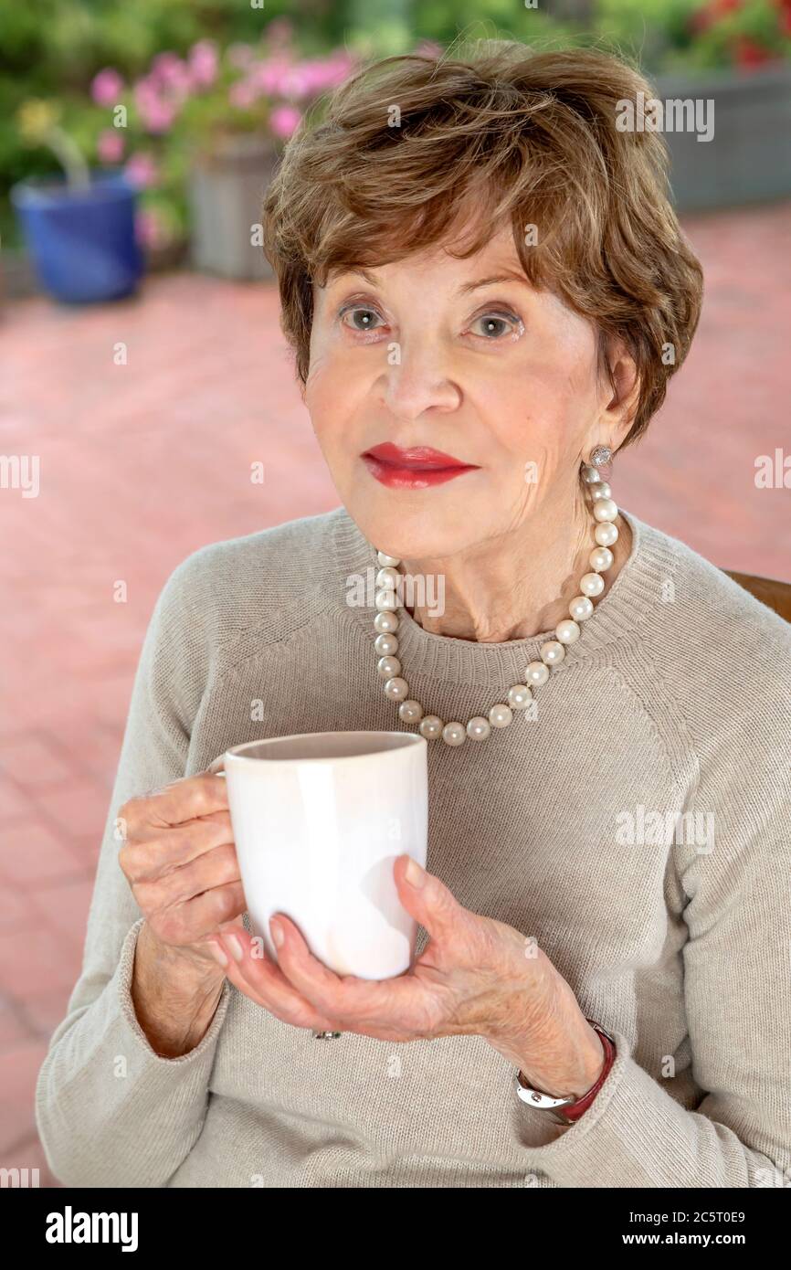 Ottant'anni donna che tiene una tazza Foto Stock