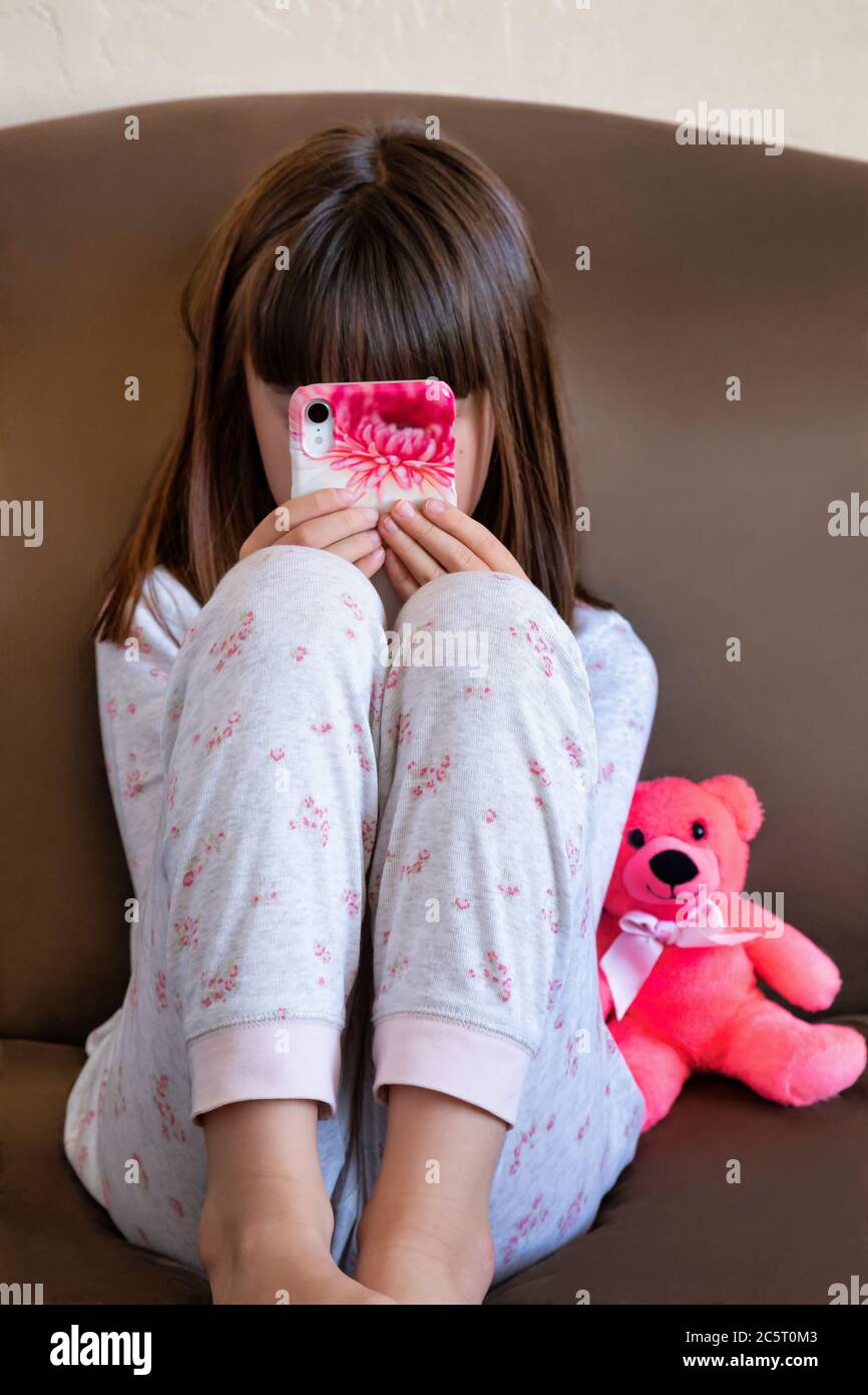 Ragazza di otto anni che gioca su uno smartphone Foto Stock