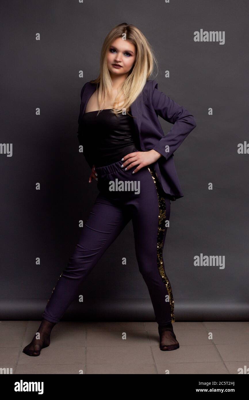 Ritratto di una bionda su sfondo grigio Studio, in un vestito viola Foto Stock