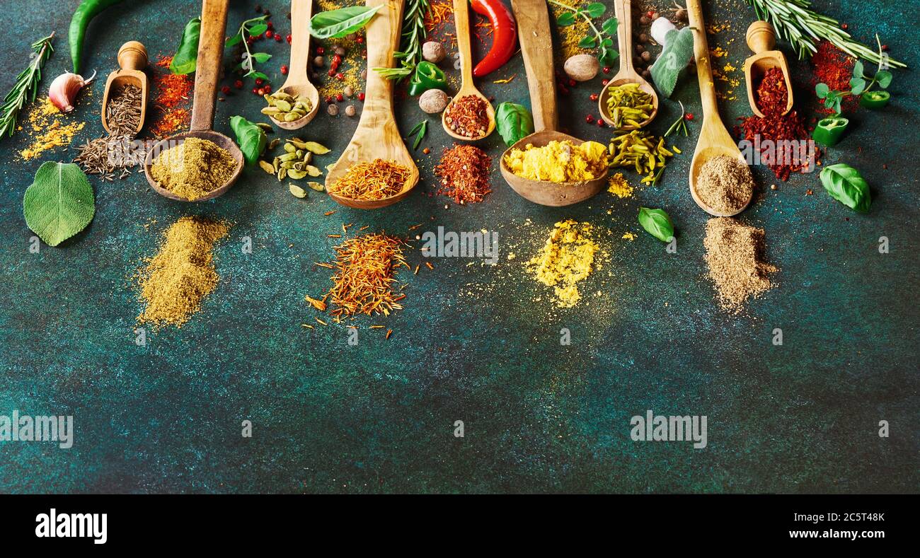Varie spezie ed erbe secche su sfondo verde scuro. Vista dall'alto delle  spezie in cucchiai di legno Foto stock - Alamy