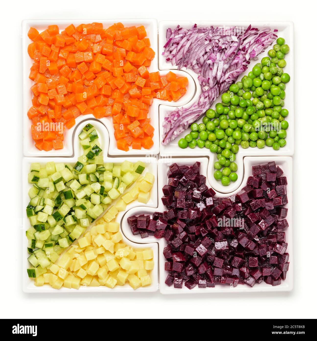 Le carote di verdure crude, i piselli, le cipolle, il cetriolo, le patate, le barbabietole tagliate a cubetti giacciono su puzzle sotto forma di puzzle e si riuniscono in un unico piatto grande Foto Stock