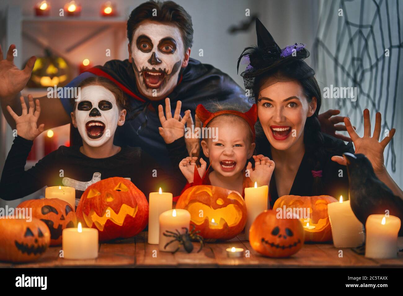 Madre, padre e i loro figli si divertono a casa. Felice famiglia che celebra Halloween. Persone che indossano costumi di carnevale e trucco. Foto Stock