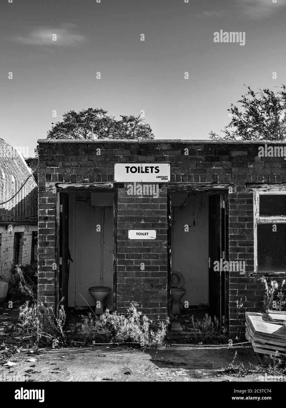 Immagine in bianco e nero di un bagno esterno parzialmente demolito del distributore di benzina di Cheshire UK Foto Stock