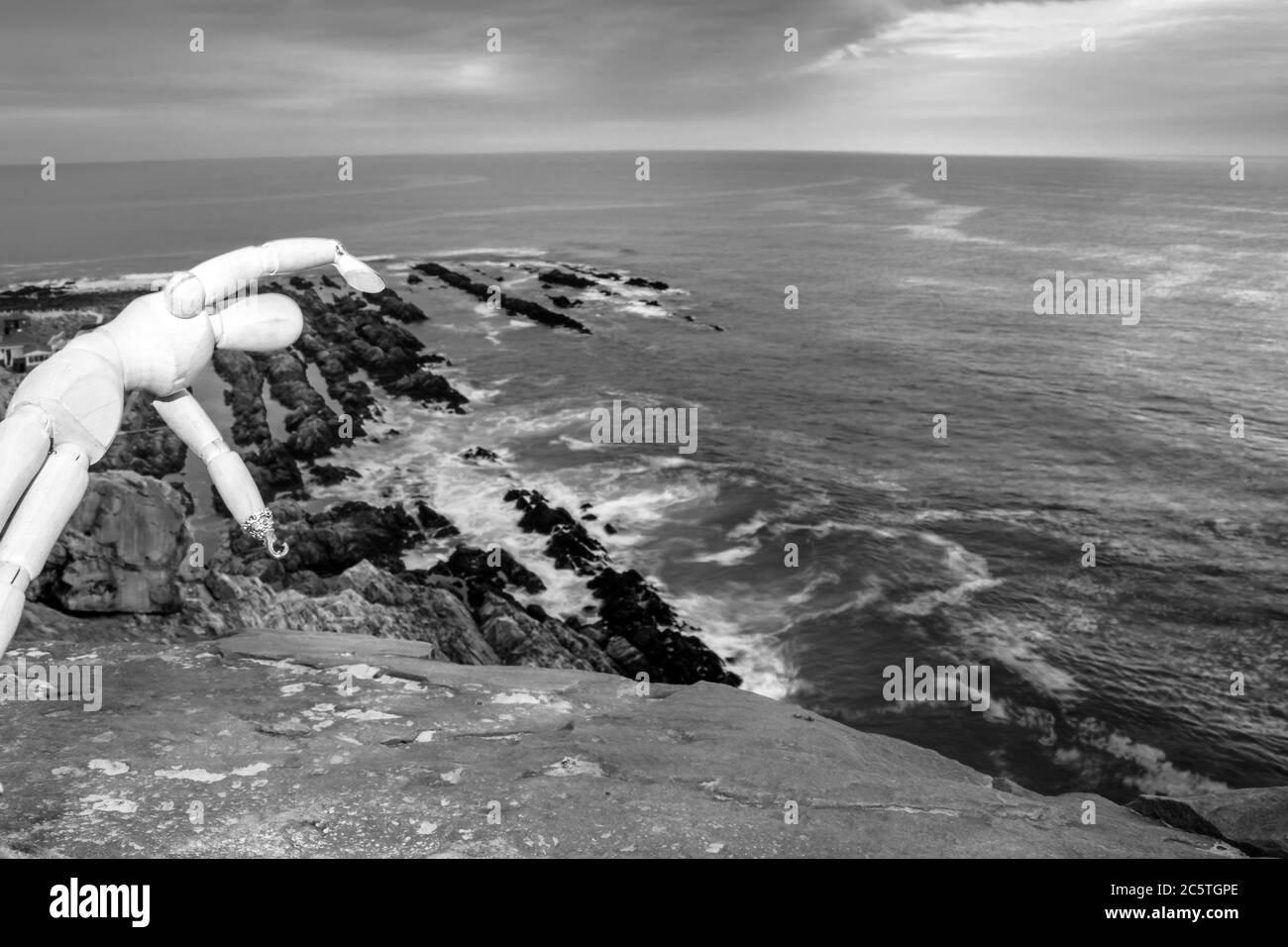 Manichino umano in legno che si posa su una scogliera con un bel mare nebbiato da un punto di vista su una spiaggia nella Baia di Mossel Foto Stock