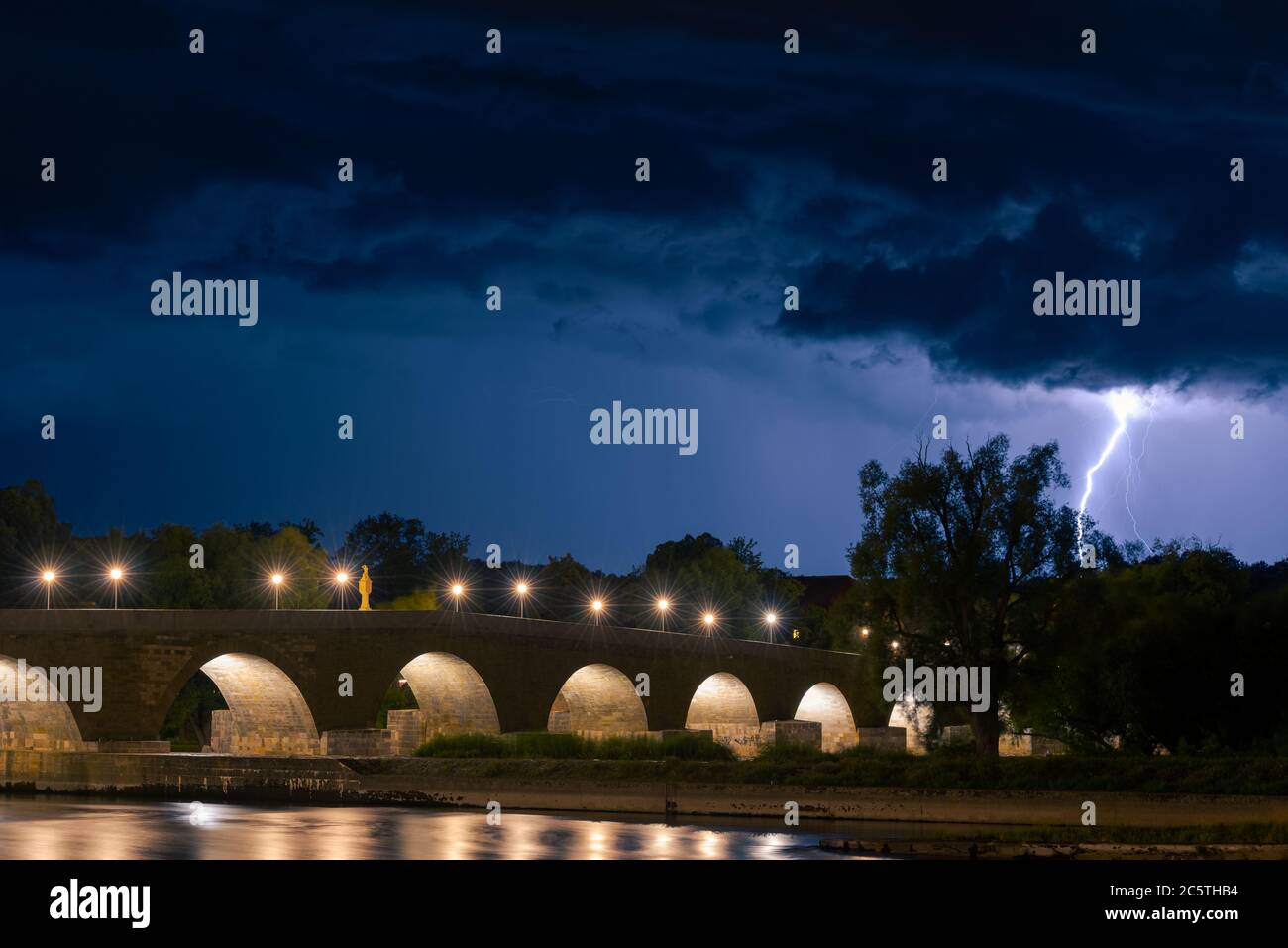 Regensburg, Baviera, Germania, storico ponte di pietra durante la tempesta estiva con lampi e fulmini di notte Foto Stock