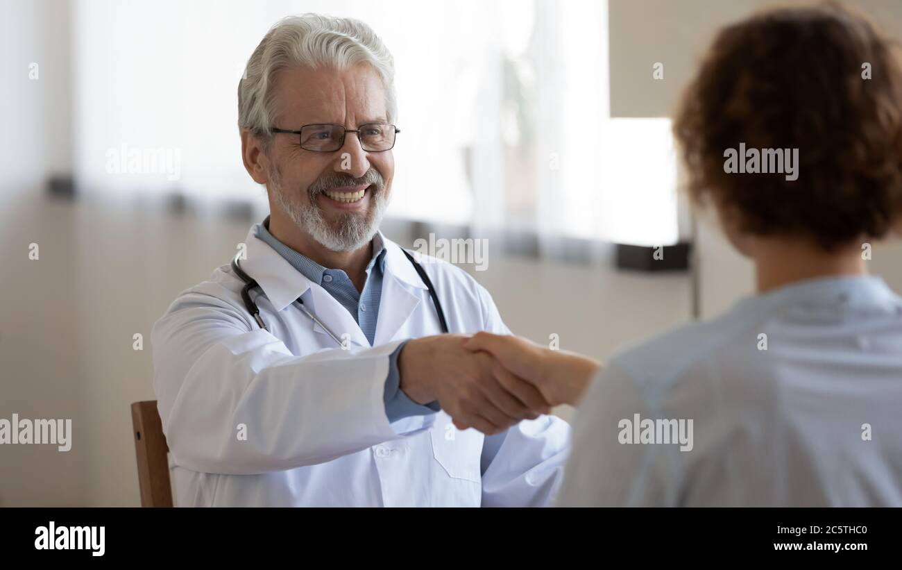 Sorridente anziano medico maschio paziente handshake alla consultazione Foto Stock