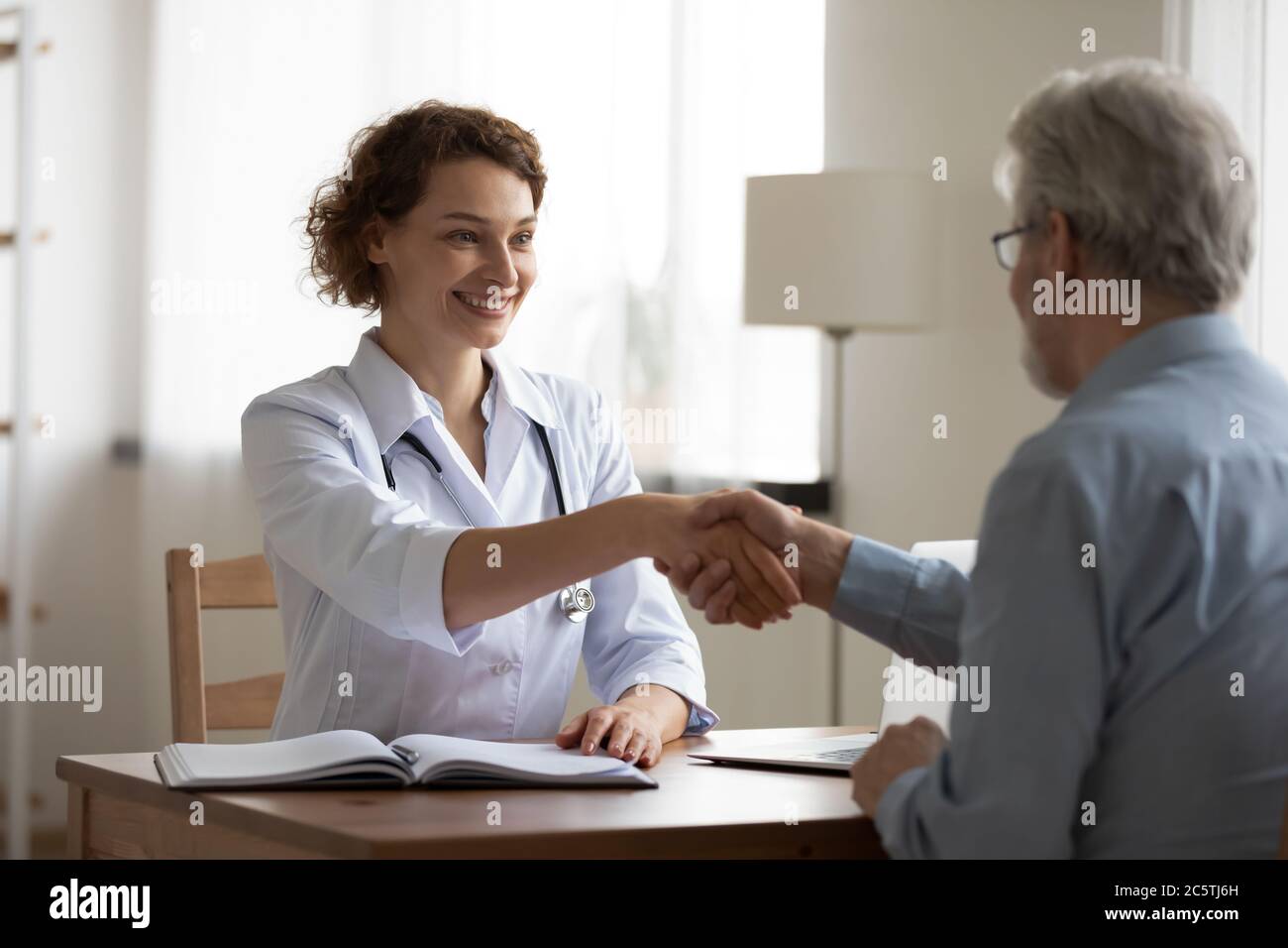 Sorridente medico donna handshake anziani paziente alla consultazione Foto Stock