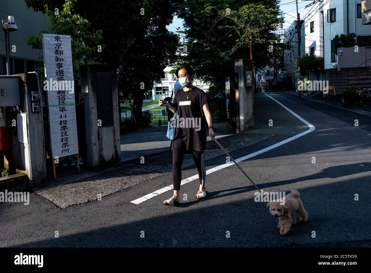 Una donna con il suo animale domestico arriva a una stazione di polling mentre indossa una maschera facciale come misura preventiva a Shinjuku.Tokyo tenendo le elezioni Gubernatoriali 2020 oggi, i residenti di Tokyo voteranno per il prossimo governatore a guidare la capitale giapponese per i prossimi quattro anni. Foto Stock