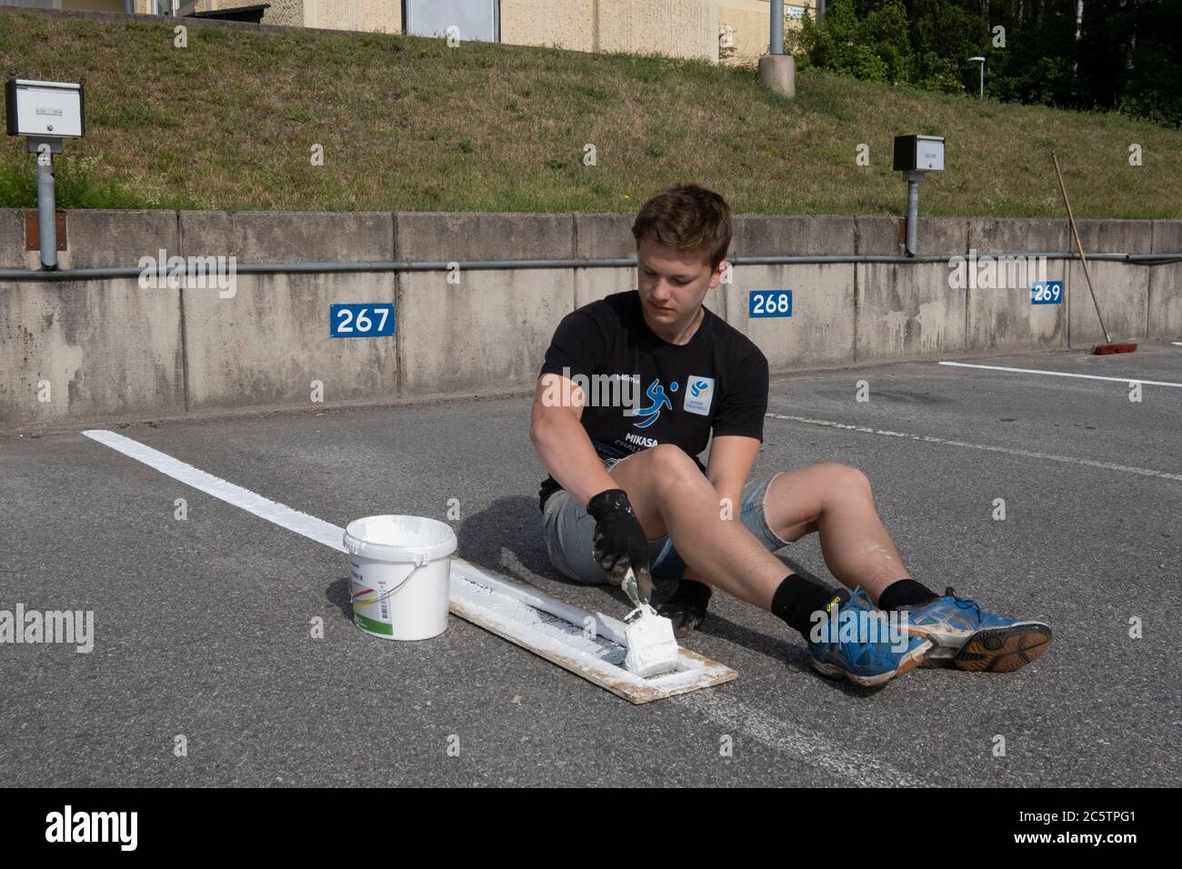 I giovani hanno ricevuto posti di lavoro estivi per dipingere le linee di parcheggio. Foto Stock