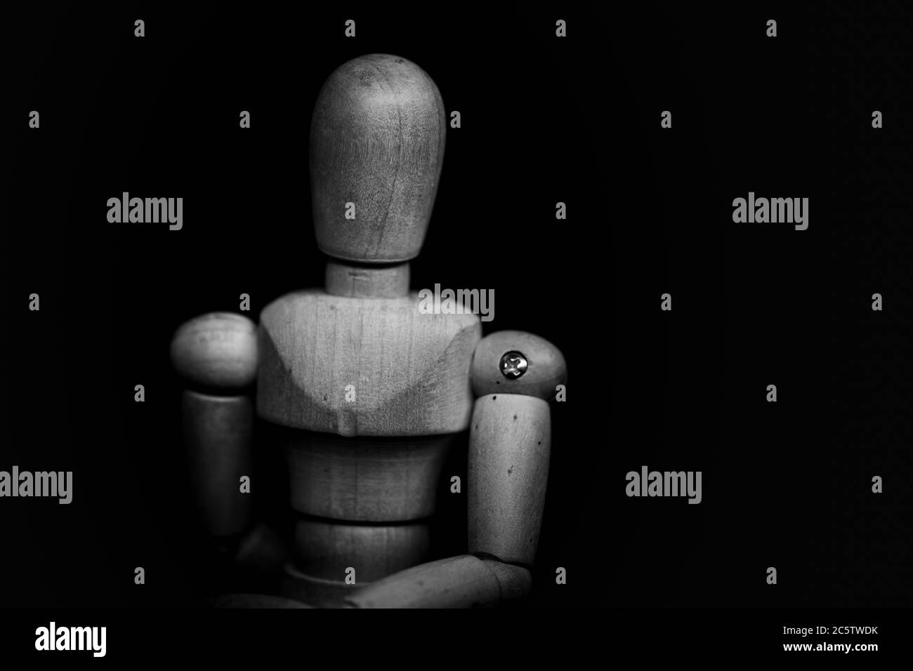 Manichino umano in legno che posa su sfondo nero Foto Stock