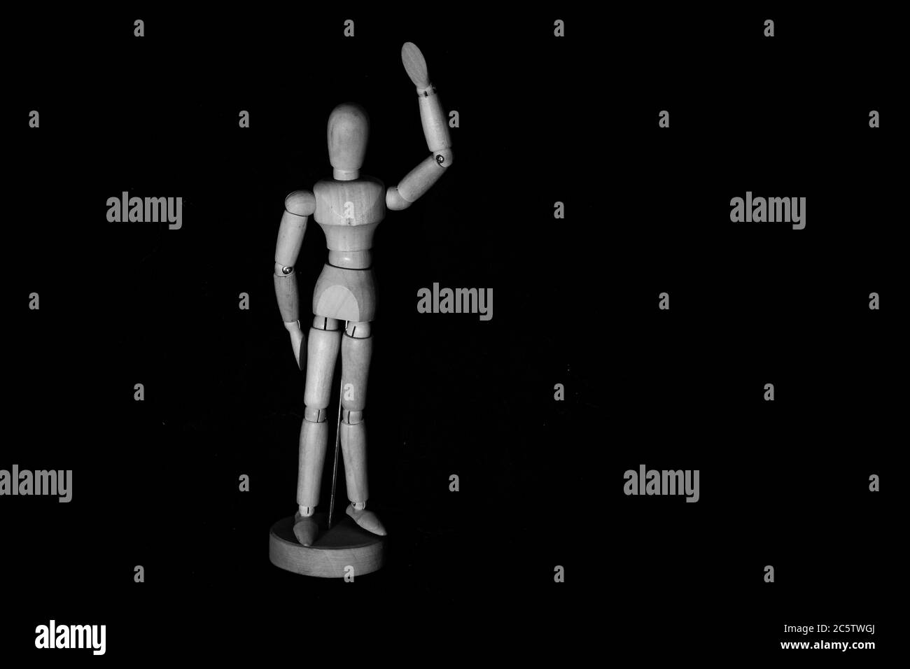 Manichino umano in legno che posa su sfondo nero Foto Stock