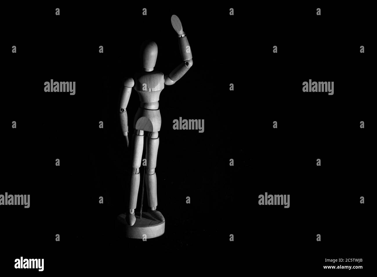 Manichino umano in legno che posa su sfondo nero Foto Stock