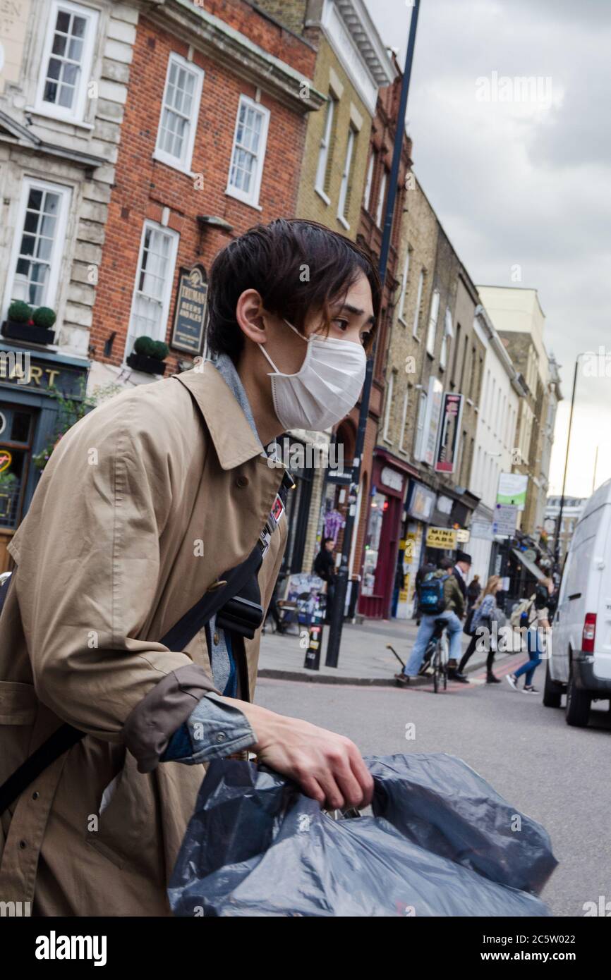 Ragazzo cinese che indossa una maschera di influenza per strada Foto Stock