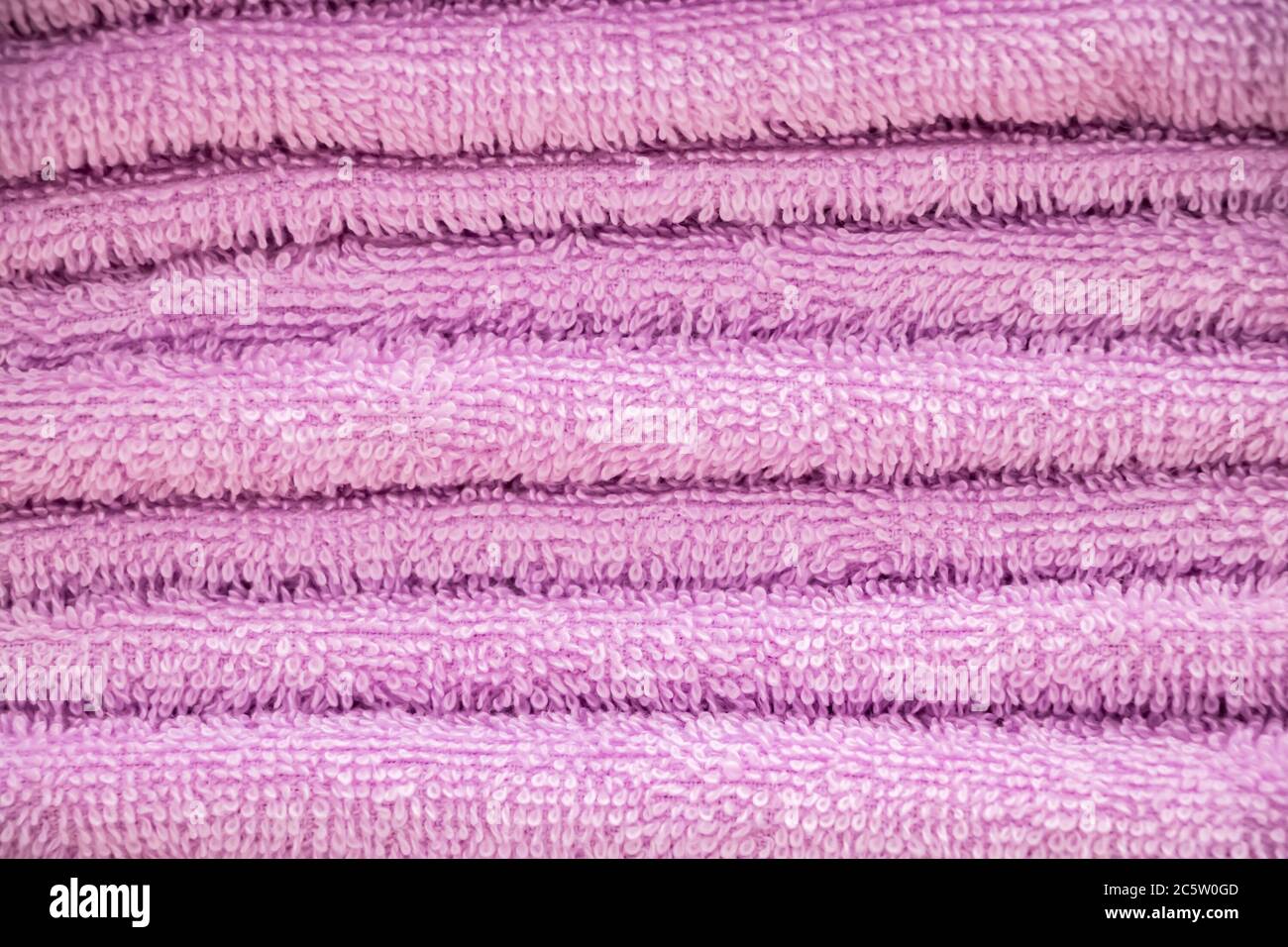 Primo piano con asciugamano rosa in spugna. Una pila di accessori per bagno morbidi. Foto Stock