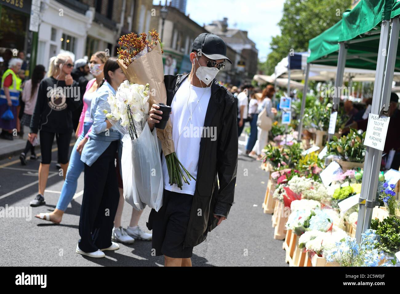 La gente cammina attraverso il mercato dei fiori di Columbia Road, Londra, mentre riapre dopo l'allentamento delle restrizioni di blocco del coronavirus in tutta l'Inghilterra. Foto Stock