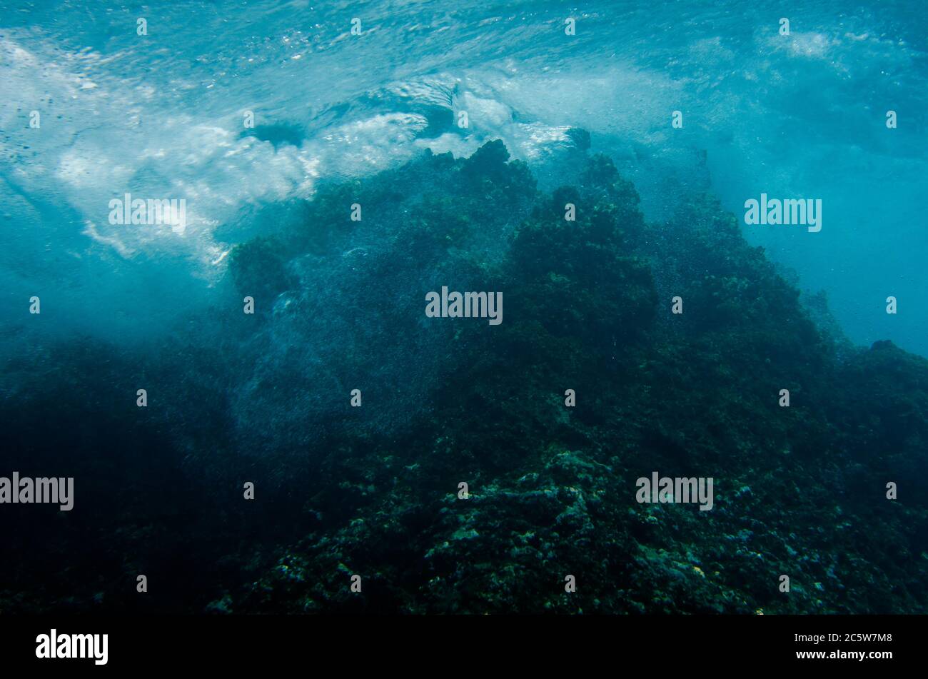 Onde che si infrangono sull'isola, Tiga Batu sito di immersione, Bangka Island, Sulawesi settentrionale, Indonesia, Oceano Pacifico Foto Stock